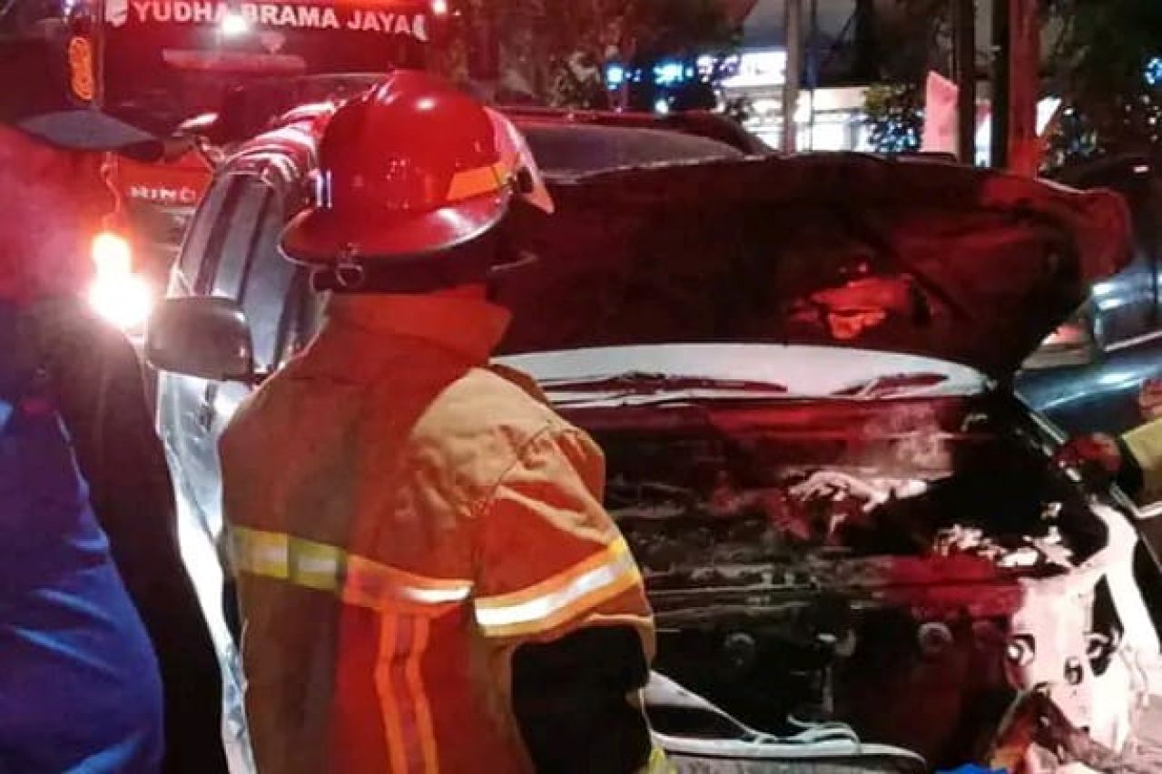 Petugas saat memadamkan api yang sedang mobil Avanza