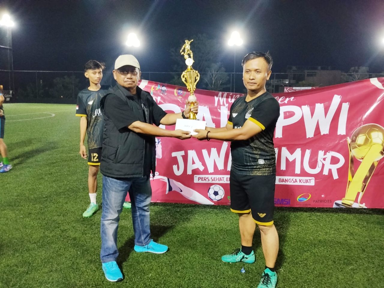 Kapten tim Judes FC (kanan) menerima Piala PWI Jatim dari Ketua PWI Jatim Lutfil Hakim.